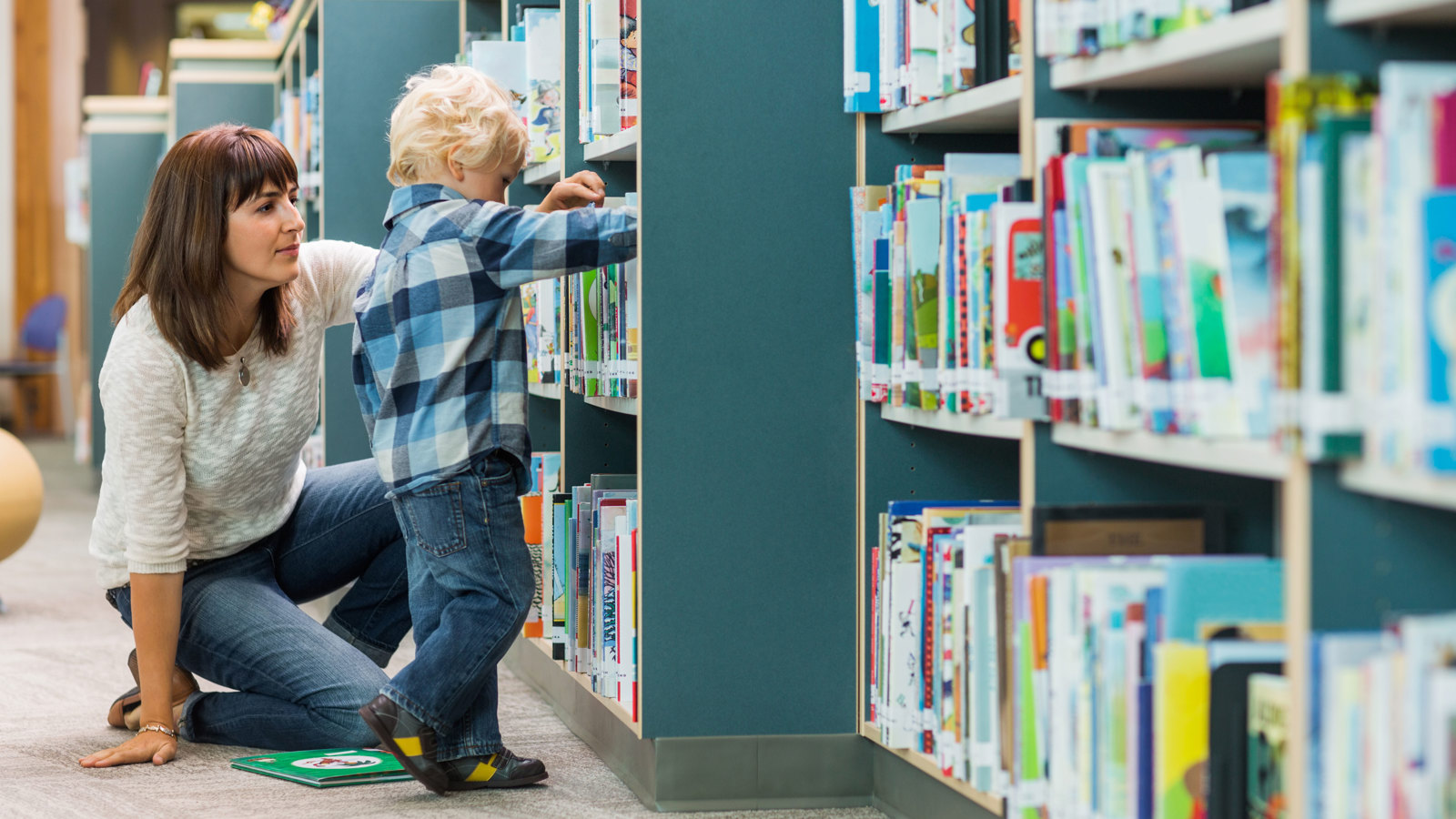 Vuxen och barn vid hyllorna i ett bibliotek