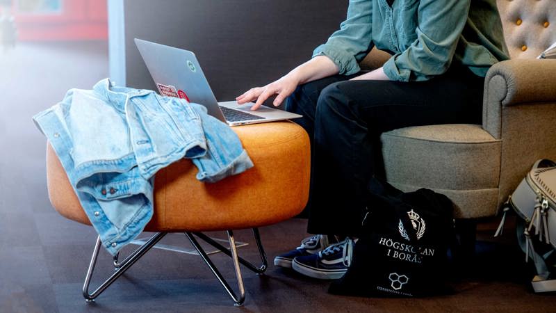 Closeup of laptop on stool and legs from students next to it