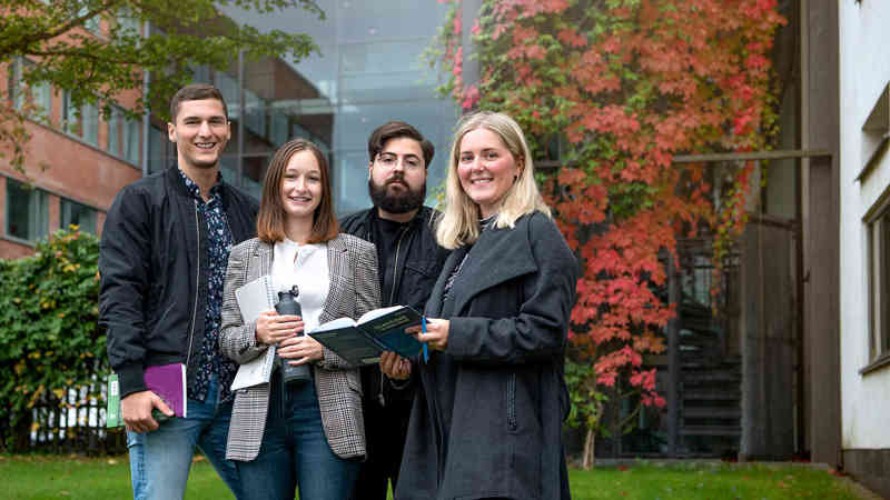 Four happy alumni outside campus