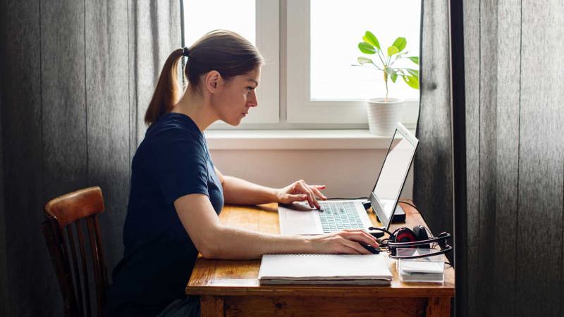 Woman working at a computer by a home desk