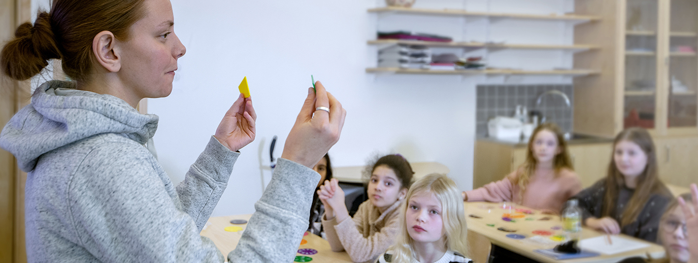 Lärare längst fram i kassrummet framför barn